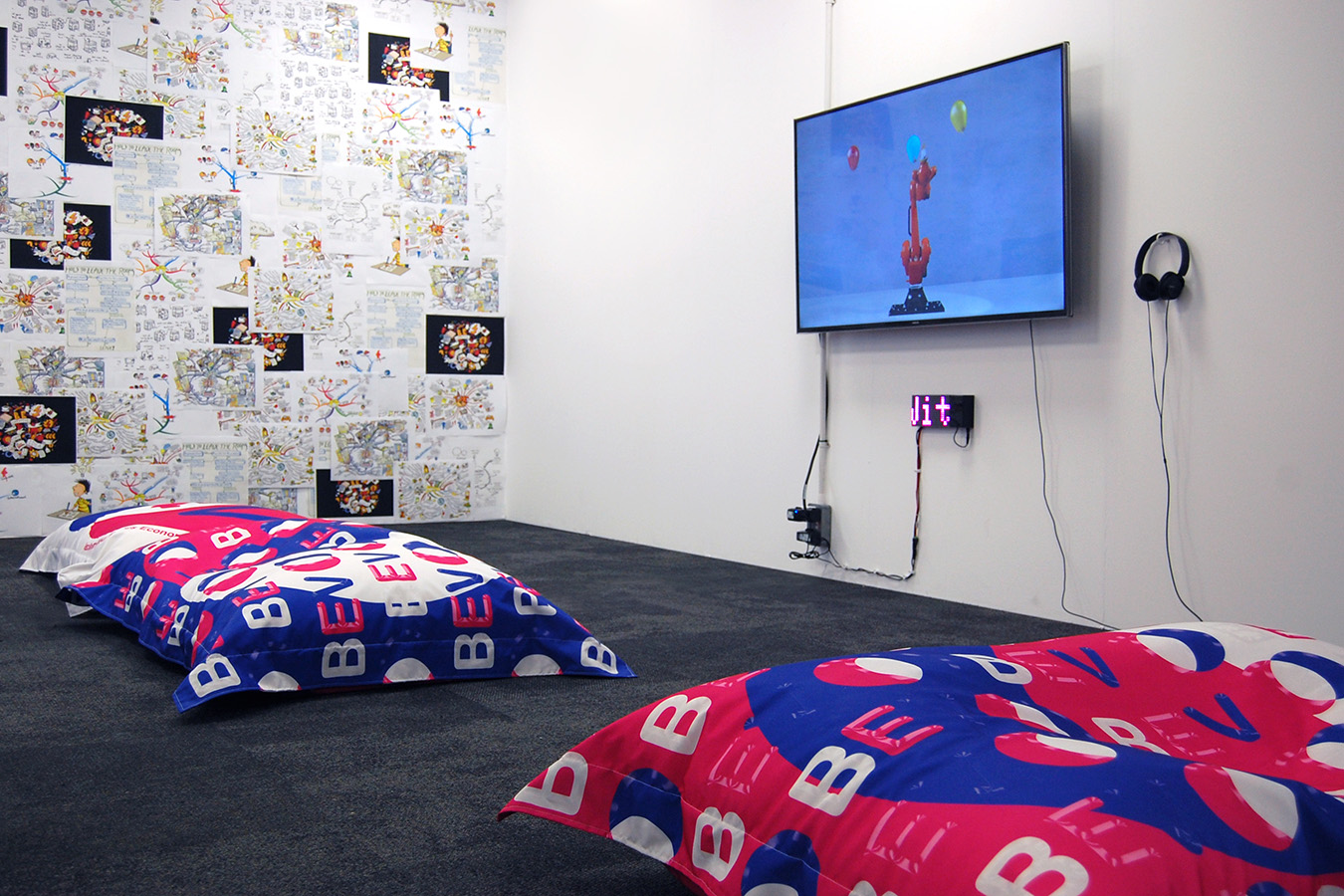 Two BEV bean bags in a room in front of a tv screen with a ticker display.