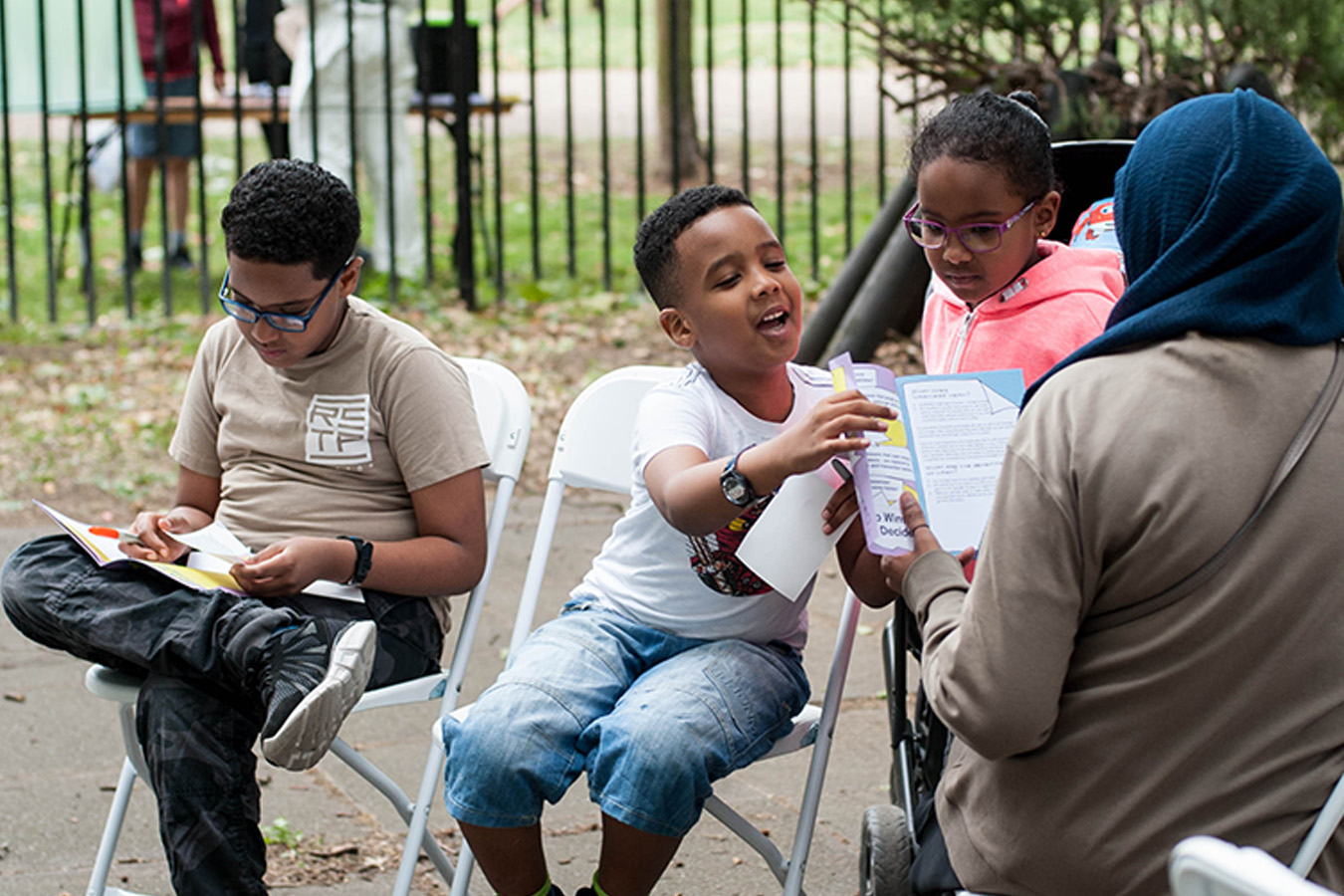 Children and their parent reading the planet cashless booklet