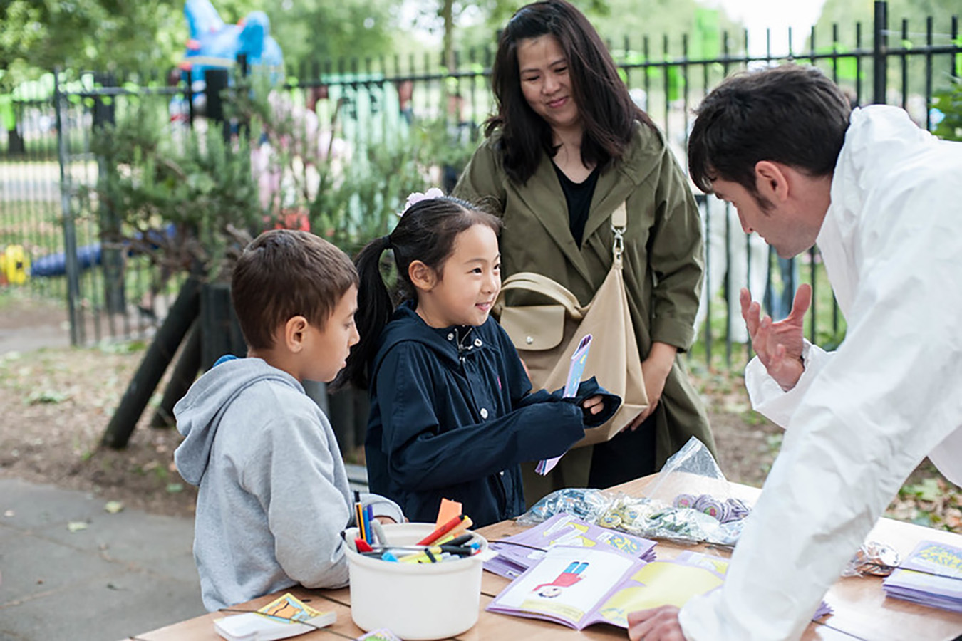 Children holding the planet cashless booklets at and event talking to one of the team who helped run the event