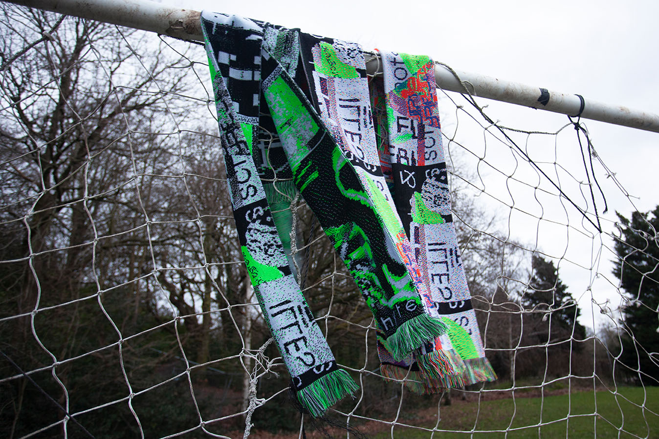 The snapshots and screenshots scarves hanging from a goal post in a park, the bright colours contrast with the background