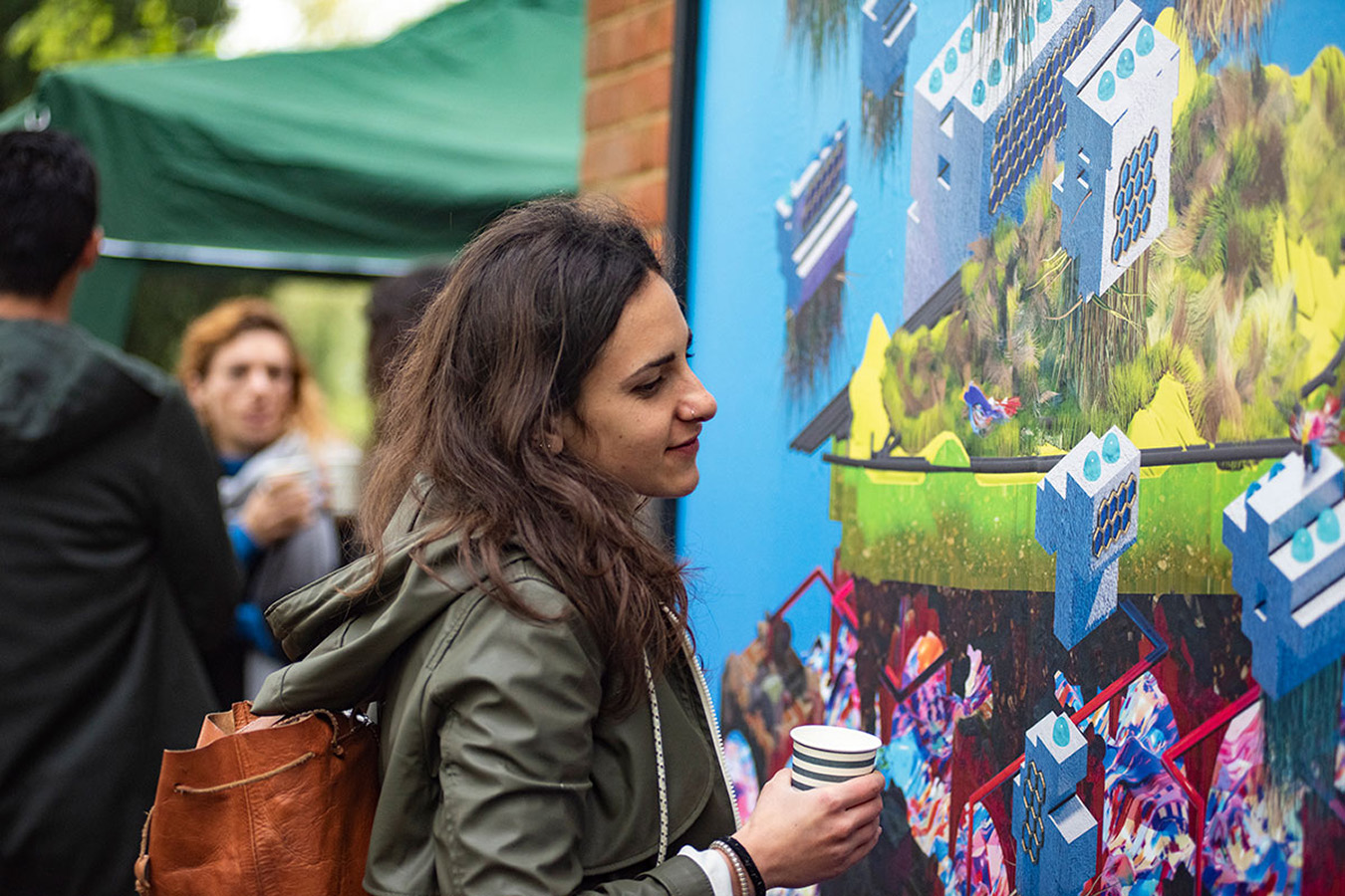 Woman looking at artwork while holding a cup