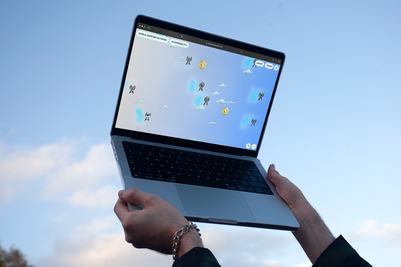 alt: A person holding a laptop up to the sky which has the world weather network website on display